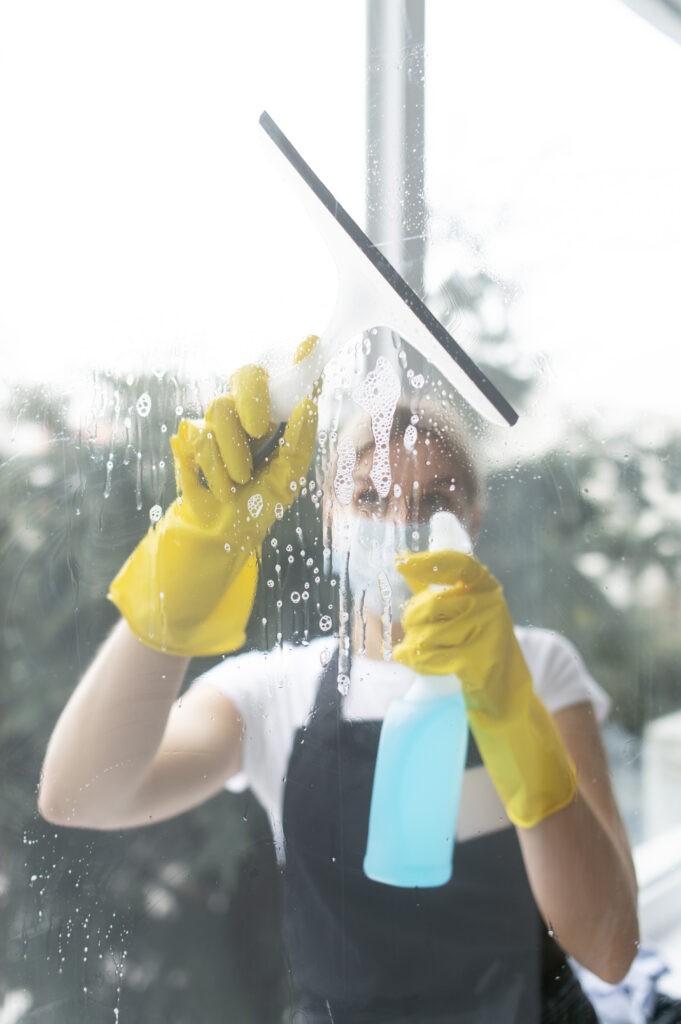 Mujer limpiando un cristal con guantes puestos